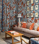 Maximalist design at the Christopher Farr Cloth Kings Road showroom, featuring Carnival Coral as curtains, wallpaper, and on the sofa. A bold fusion of vibrant colour and botanical patterns creates a dynamic and expressive interior. Photography by Antonia Blunt.